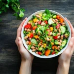 A vibrant top-down shot of a colorful and textured dense bean salad in a white ceramic bowl